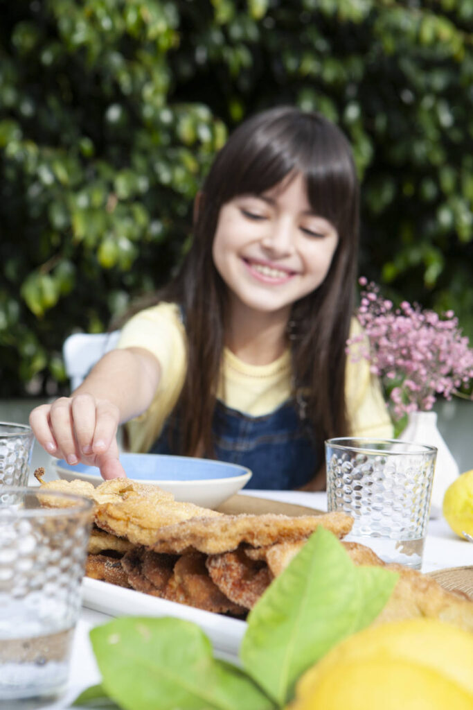 Una niña disfrutando de un plato de paparajotes, postre típico de la gastronomía regional elaborado a base de huevo, leche, raspadura de limón (y su correspondiente hoja), harina, levadura, azúcar y canela